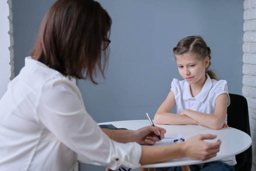 Woman takes notes while talking with a young girl.