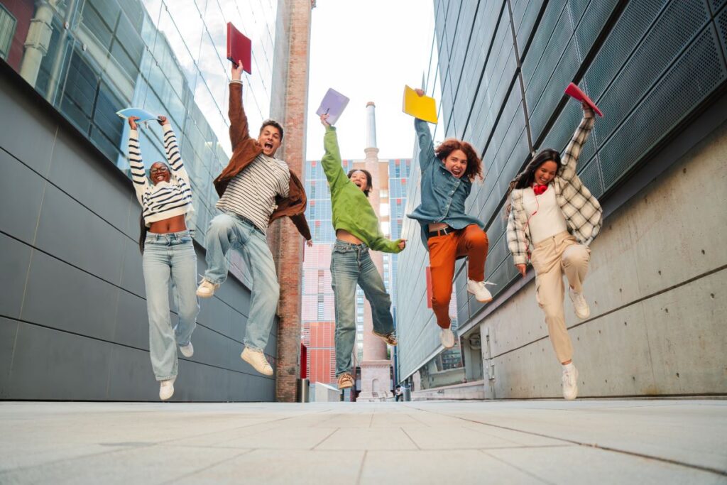 A group of students happily jump in the air holding their textbooks.
