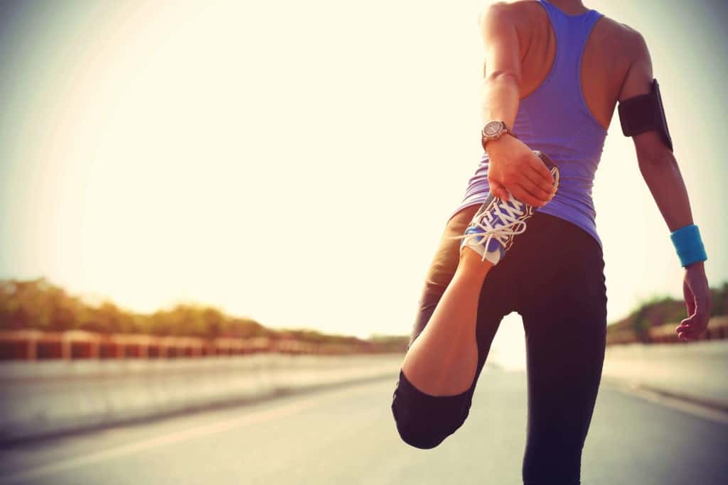 A woman in workout attire stretching before a run outside.