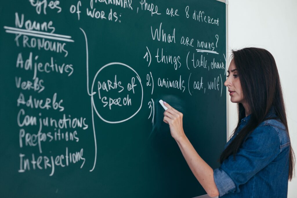 An English teacher writes on the chalkboard in class.
