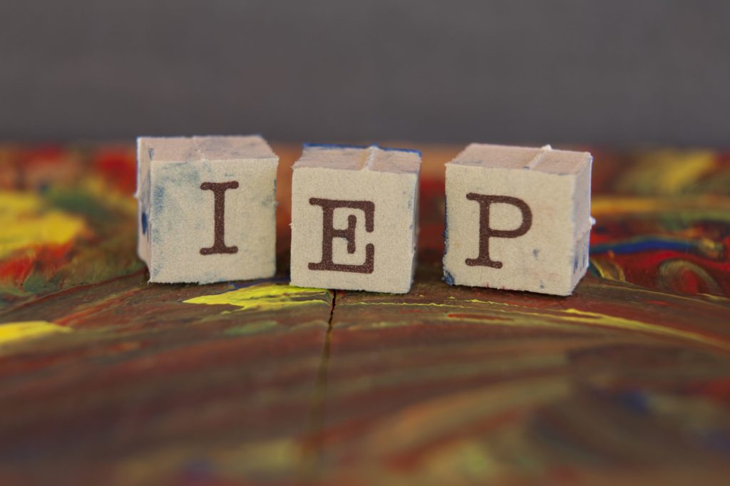 Block letters spelling ‘IEP’ on top of painted table.