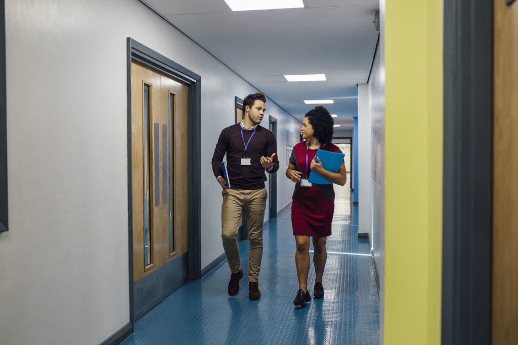 Two teachers talk in the school hallways as they walk to their next lesson.