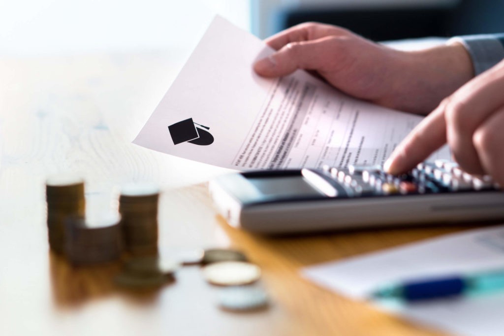 A student counts their money with a calculator while holding tuition paperwork.