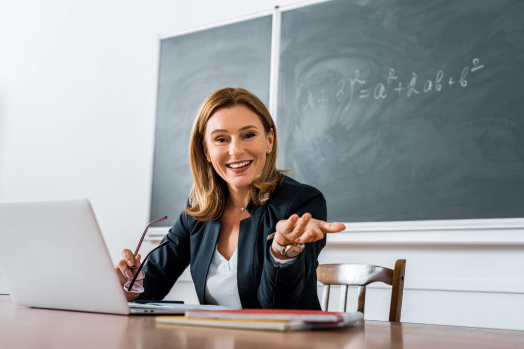 A female teacher sits at her desk, working on her lesson plans.