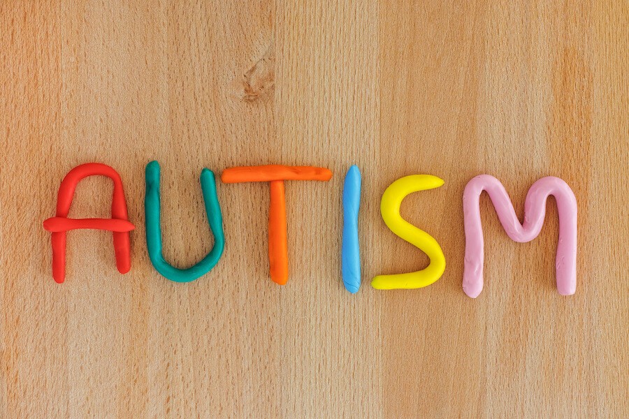 “Autism” spelled out in colorful clay on a wooden table.