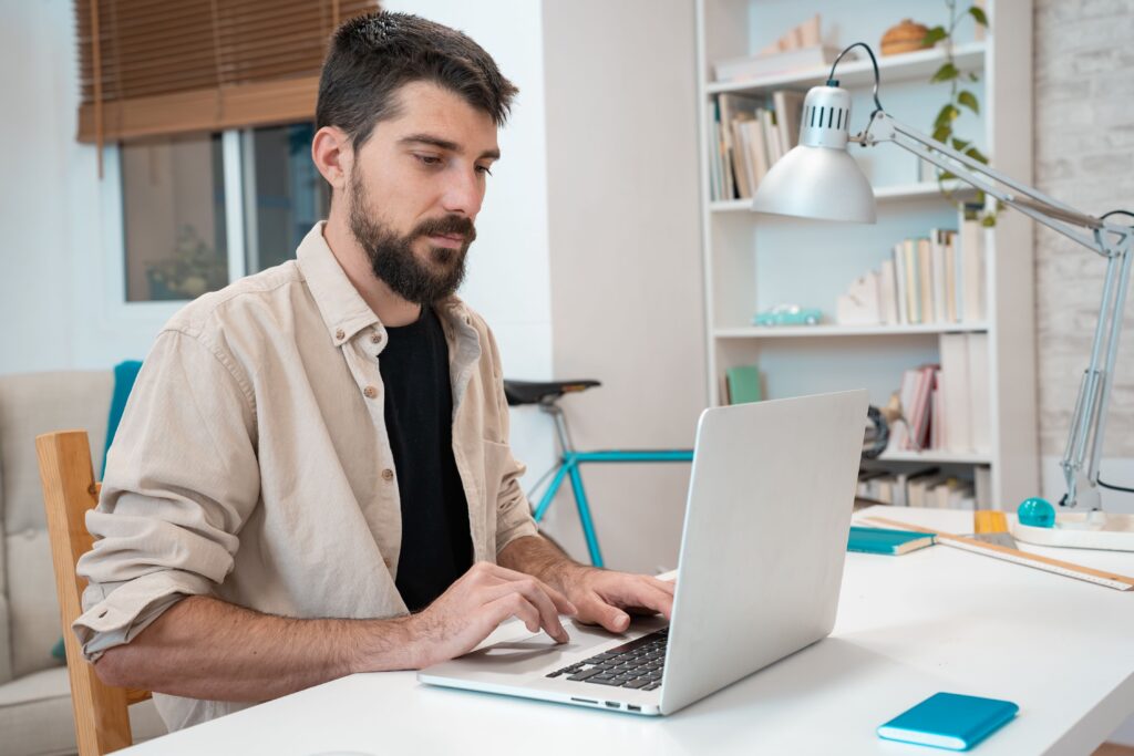 A man sits at his desk at home on his computer.