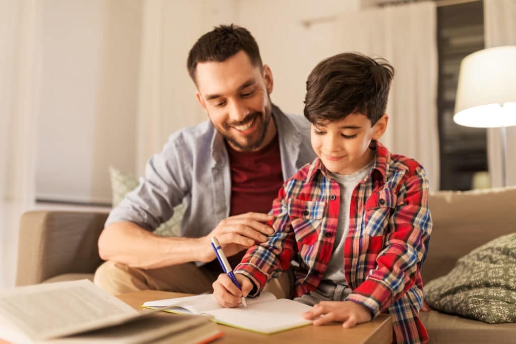 Dad helping his young son with writing.