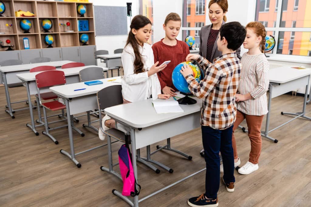 Group of students looking at a globe with their teacher.