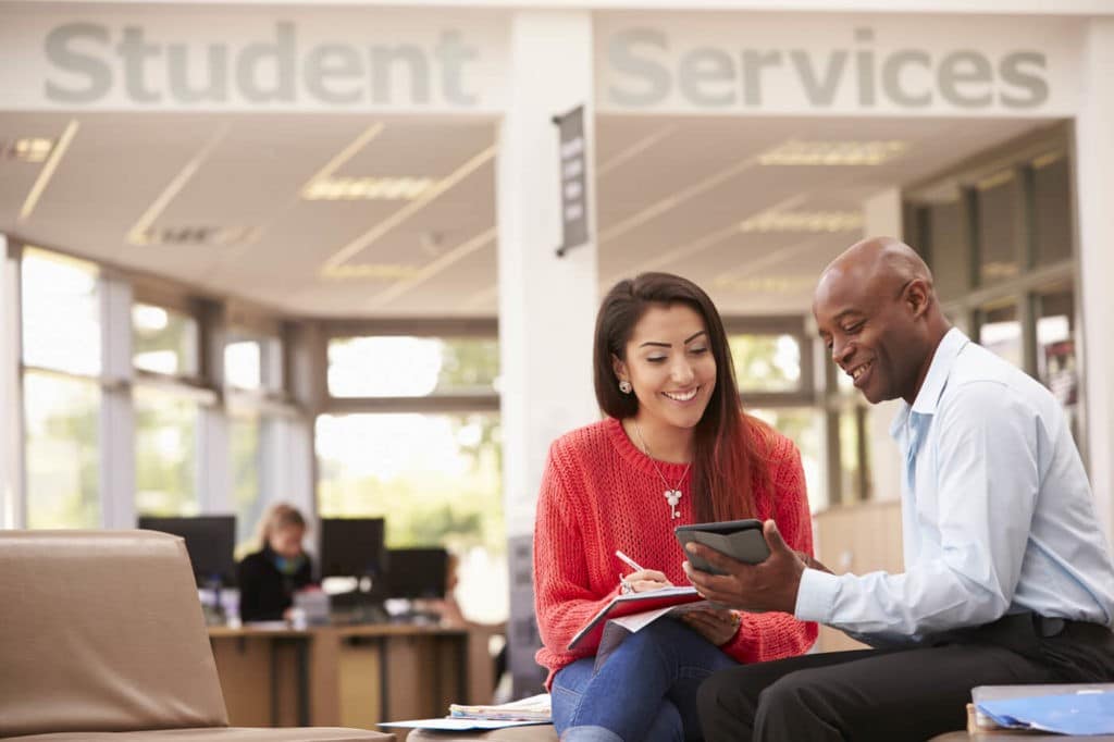 Older gentleman helping a young woman outside of student services.