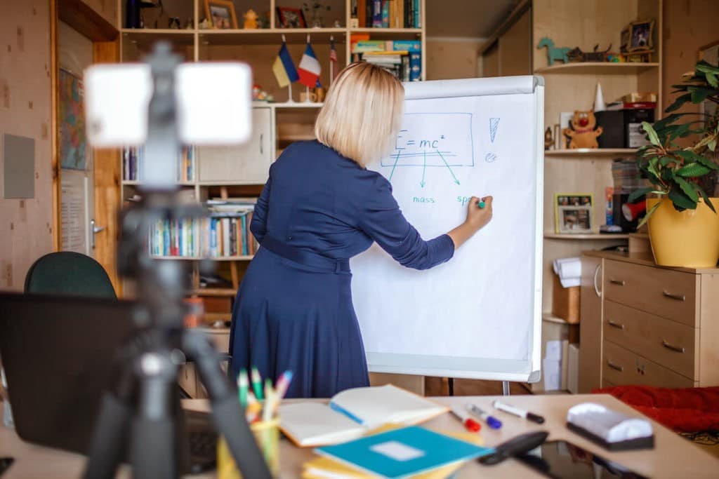 A teacher writing on a giant note pad while instructing virtually.