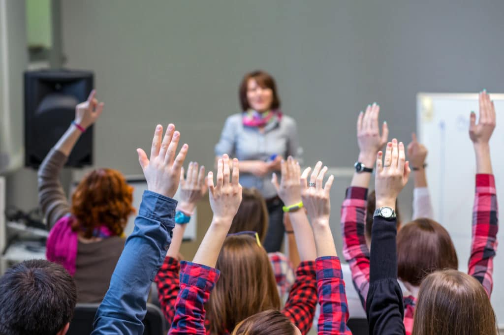 Classroom with students raising their hands