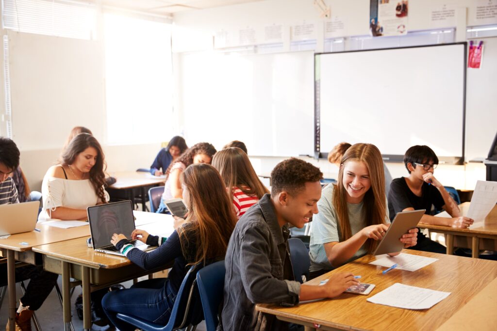 A wide angle shot of a classroom of high school students using Chromebooks and tablets.