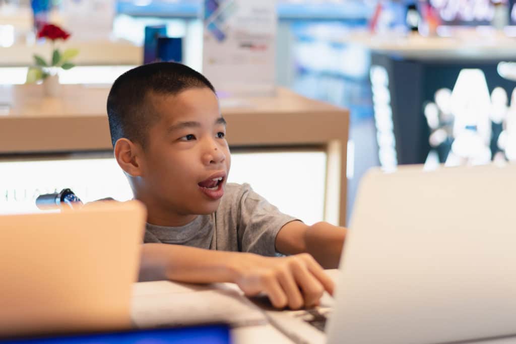 Young disabled boy in a wheelchair working on a laptop.