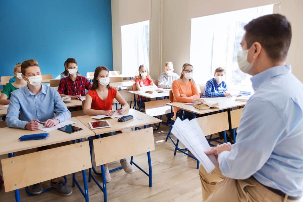 Class of students wearing masks with a masked teacher at the front.