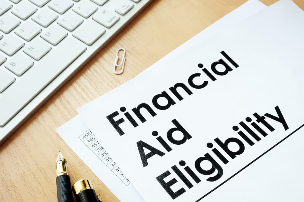 Paper reading ‘Financial Aid Eligibility’ on a table next to a pen and keyboard.
