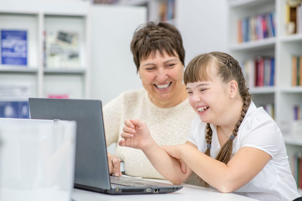 A teacher works directly with her special education student on a laptop.