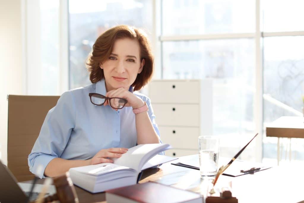 A professional sits at her desk, reading.
