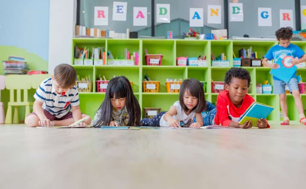 Students read books in the classroom on the floor.