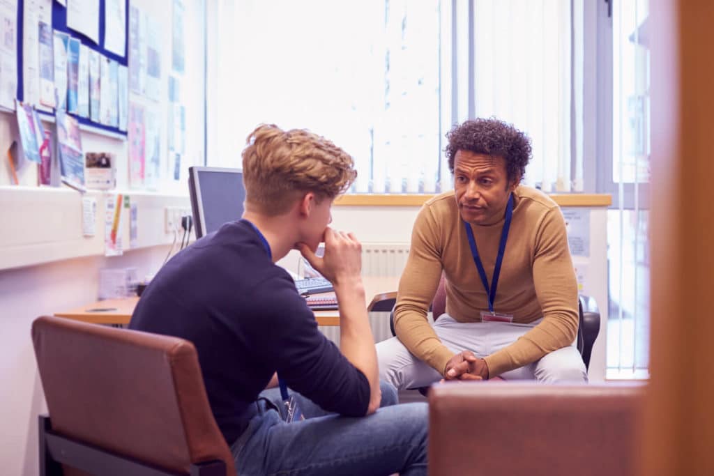 Counselor sitting in their office talking with a student.