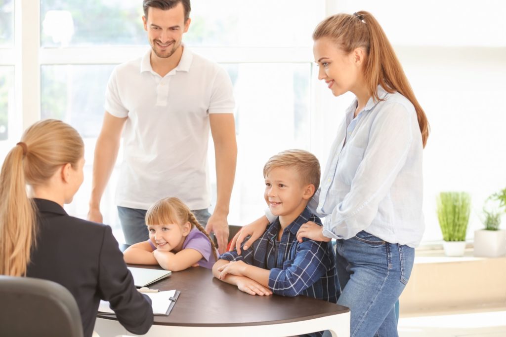 A young couple meets with the principal at school, all smiling.