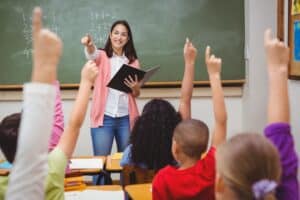 A group of students raising their hands to answer a question.