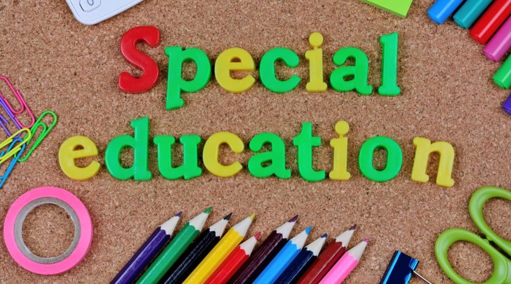 Words special education spelled out on a corkboard, with colored pencils below it.