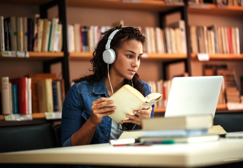 Young student studies in a library, using a laptop and learning online.